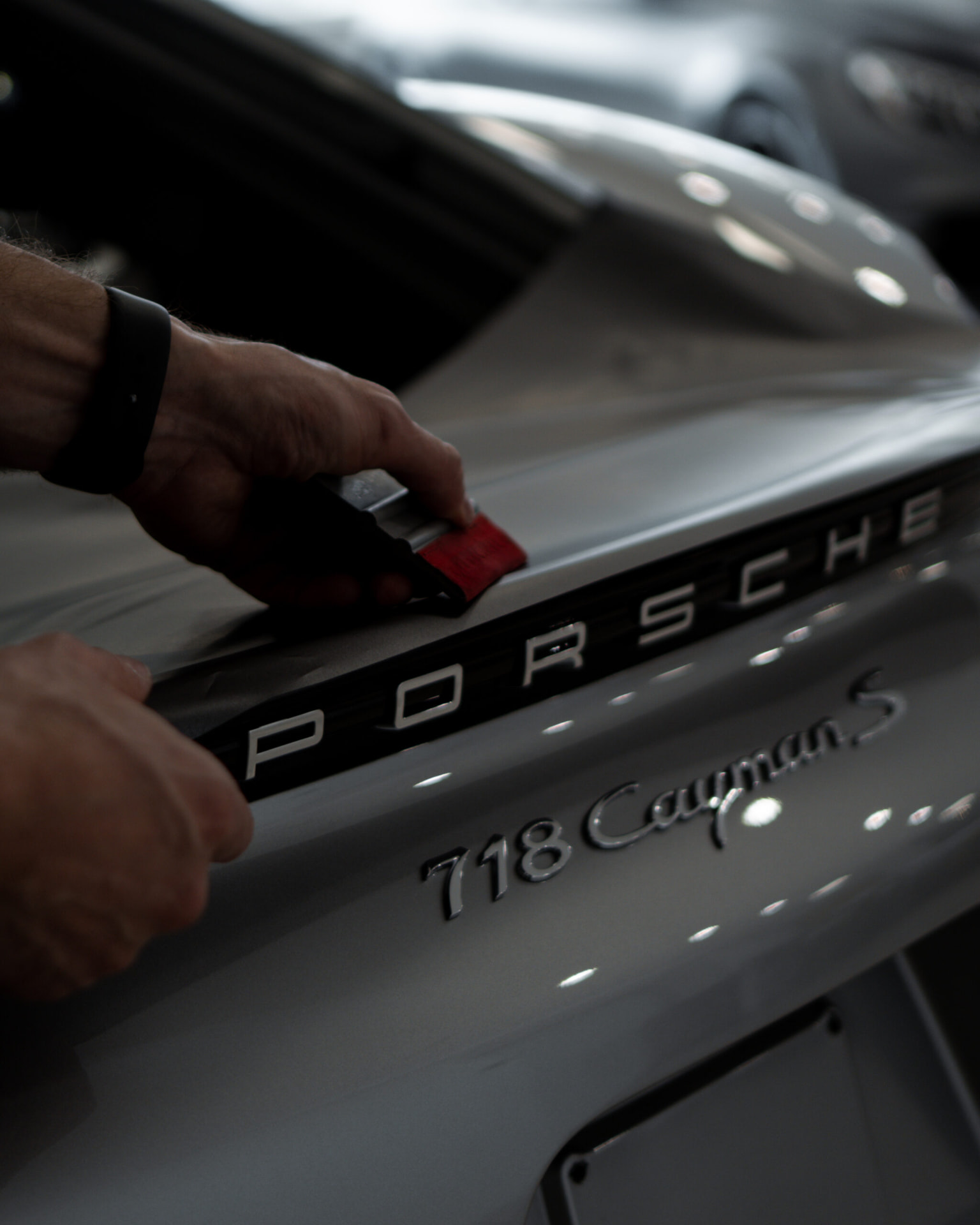 Paint protection film being applied to a Porsche 718 Cayman rear panel