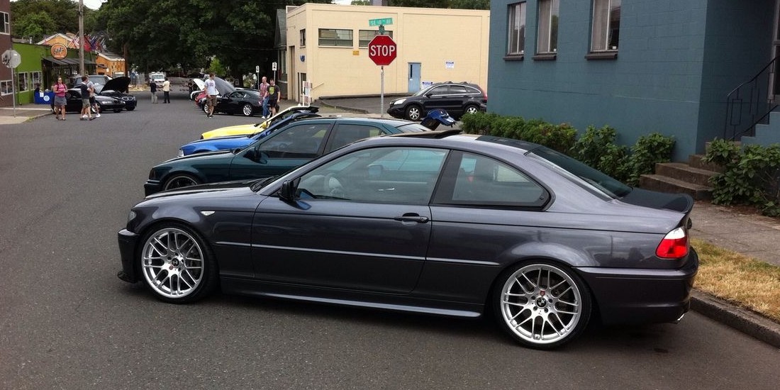 A dark grey BMW M3 coupe lowered on multi-spoke wheels at a street car meet