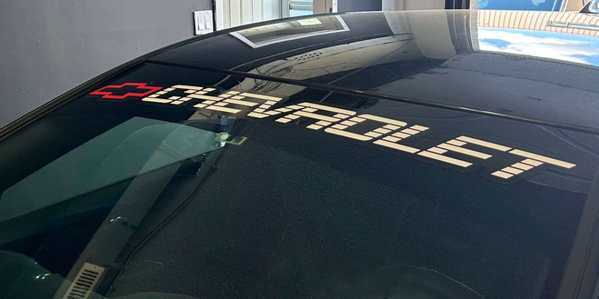 A custom white Chevrolet windshield banner decal with a red bowtie on a black car